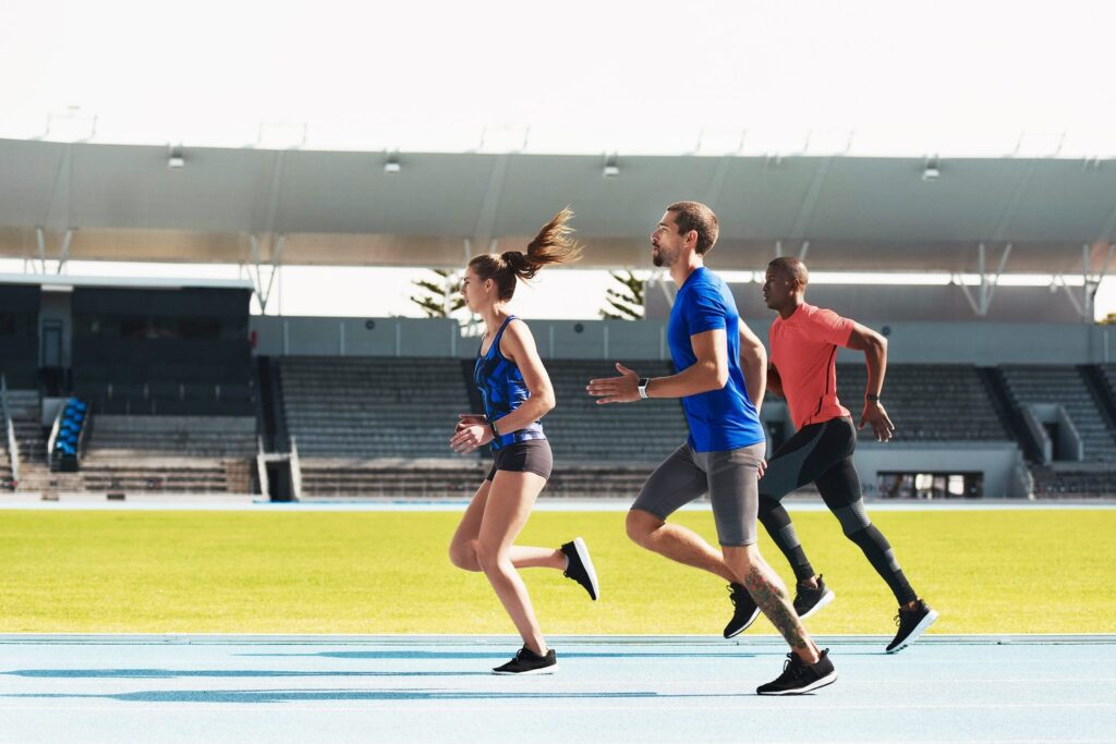 Des sportifs s&rsquo;entra&icirc;nent sur une piste d&rsquo;athl&eacute;tisme dans un stade.