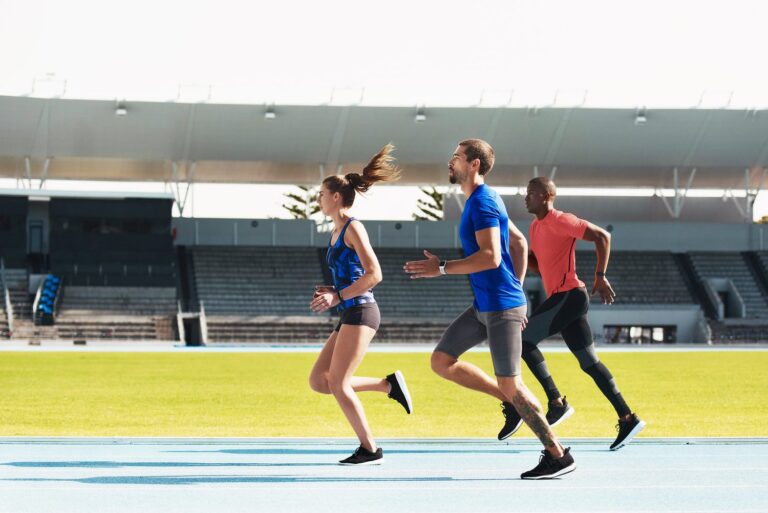 Des sportifs s’entraînent sur une piste d’athlétisme dans un stade.